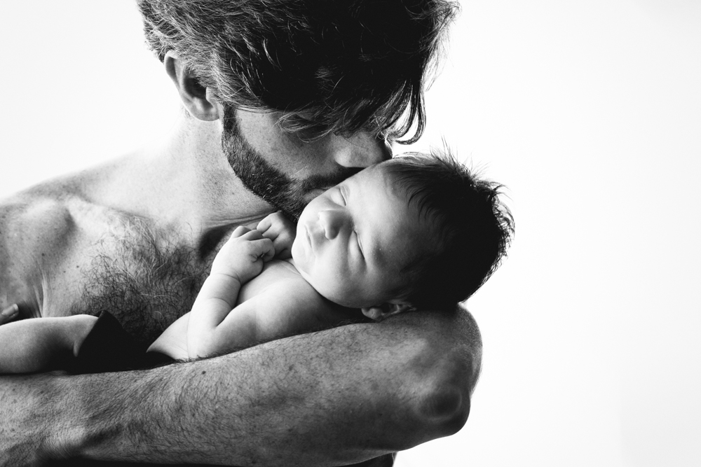 Photo de bébé nouveau né avec papa en noir et blanc en studio en high key éclairage façon aubade
